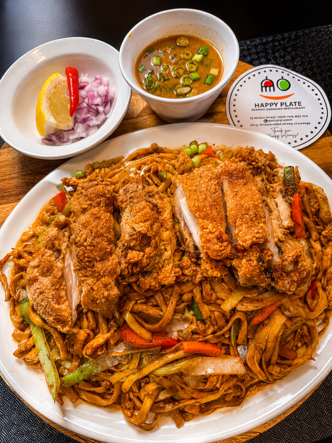 Crispy chicken over stir-fried noodles with dipping bowls