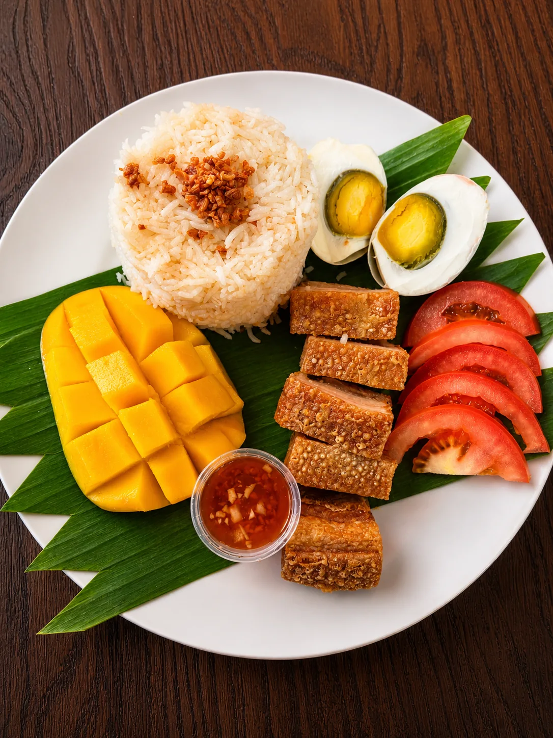 Crispy pork plate with garlic rice, mango, tomato and salted egg